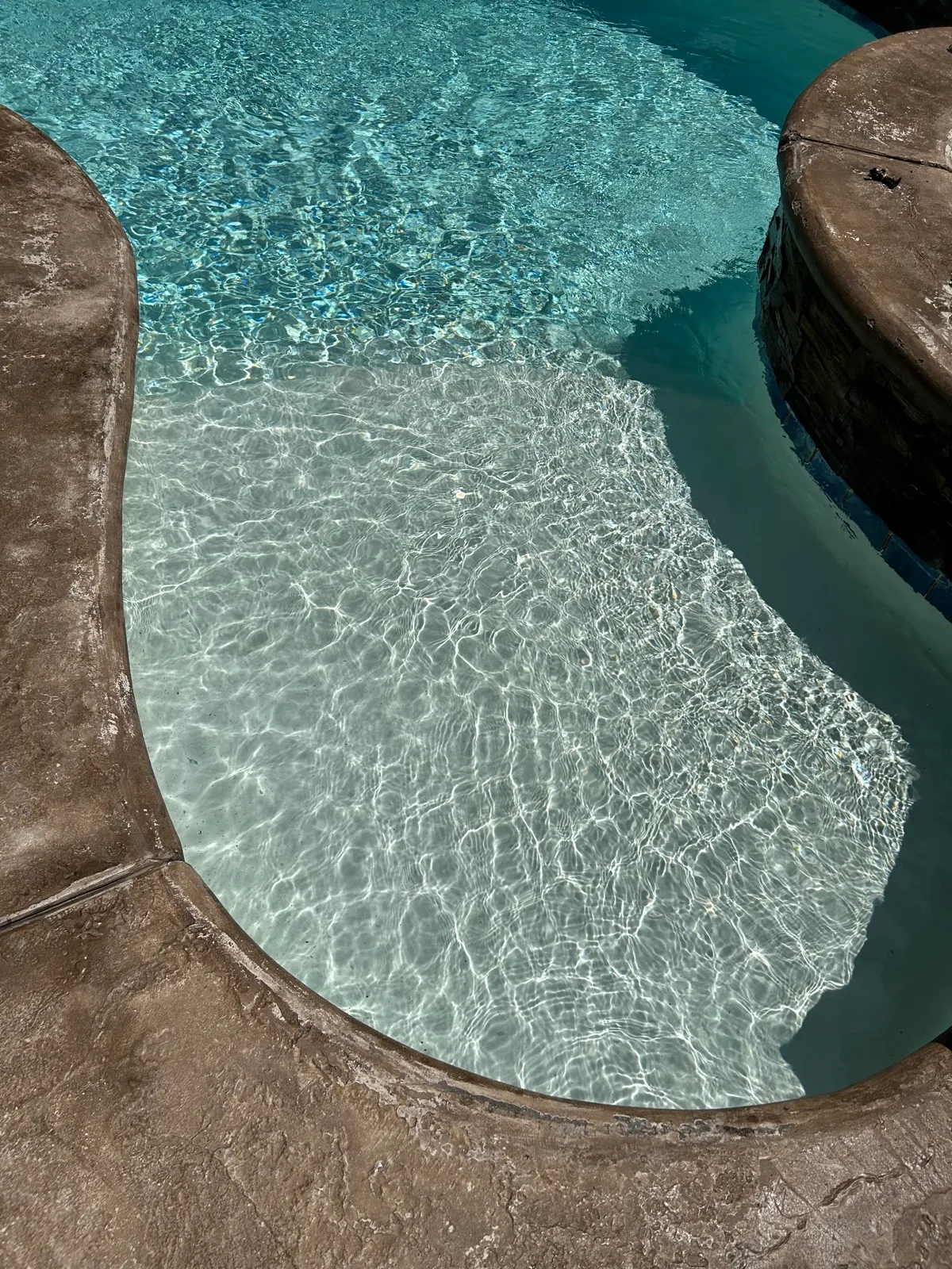 Overhead view of a pristine freeform pool with attached round spa, showing sparkling blue water after Banana Pool & Spa Service maintenance in Temescal Valley