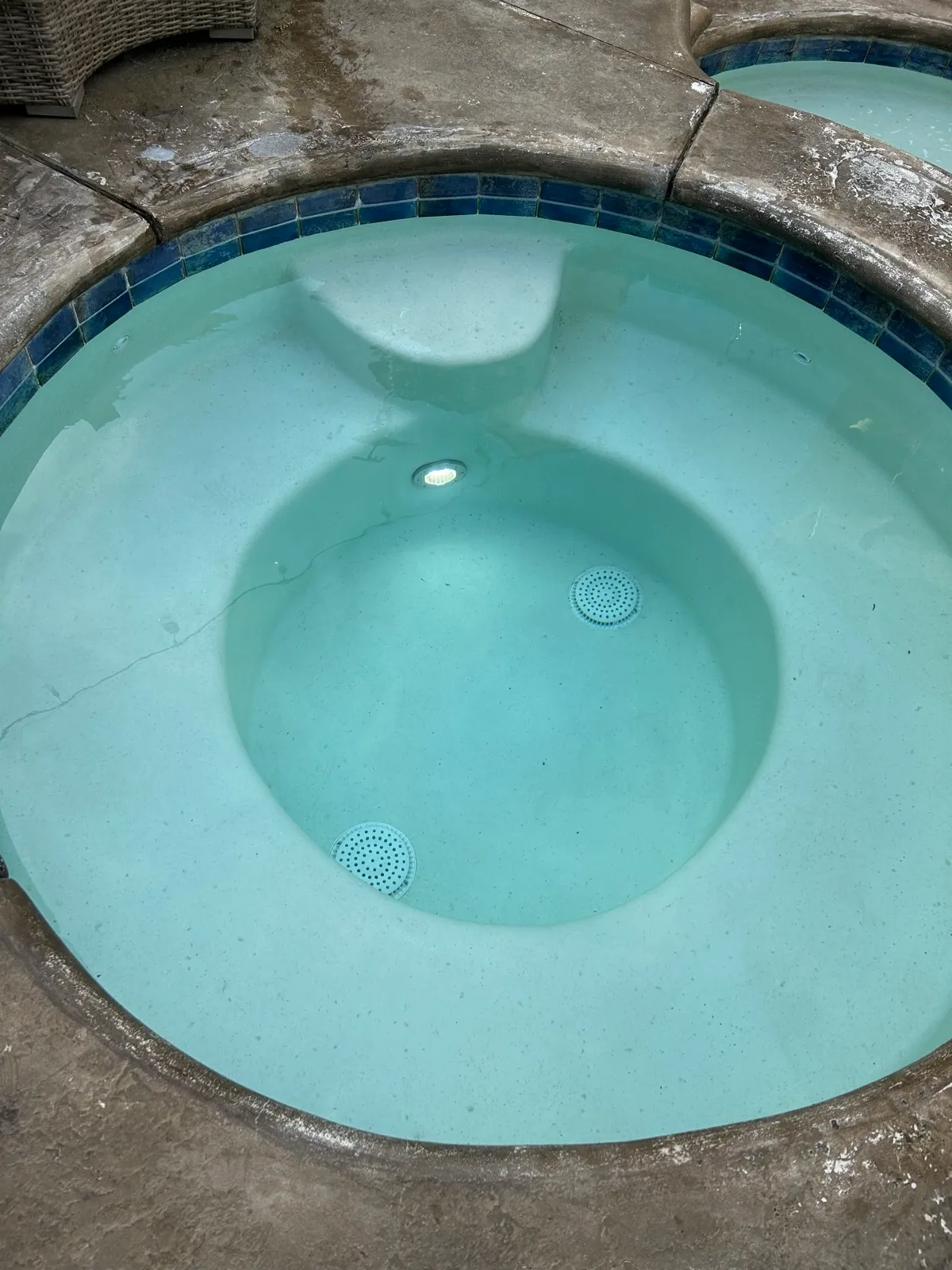 Overhead view of a round spa with cloudy, milky-white water and visible debris before professional pool and spa treatment service in Temescal Valley, CA